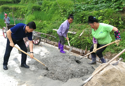 田自文（左一）正在帮助村民修进村公路的排水沟.jpg
