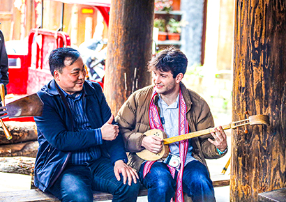 1775005647607051753.jpg 耶鲁合唱团成员与侗族歌手交流琵琶乐器弹奏。.jpg