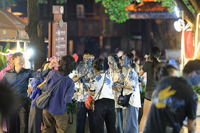 年轻游客们手持卣卣，相互追逐涂抹花脸。.jpg